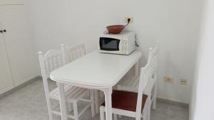 a white table and chairs with a microwave on it at Apartamento Planeta 2º centro in O Porto de Espasante