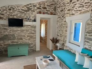 a living room with a blue couch and a stone wall at Ankon Beach House Kythnos in Kithnos