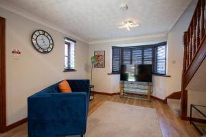 a living room with a blue couch and a clock at Eastwood in Colchester