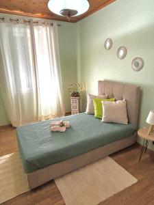 a bedroom with a bed with green sheets and a window at SokratesVilla in Mystras