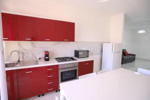 a kitchen with red cabinets and a stove top oven at Clara Apartment in Parghelia