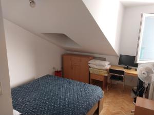 a bedroom with a bed and a desk with a computer at Apartman u Nisu in Niš