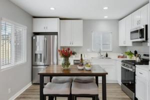 Una cocina con una mesa de madera y gabinetes blancos. en Leyla Pool Spa Min to Downtown Freeways Beaches, en San Diego