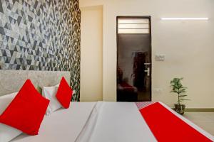 a bedroom with a white bed with red pillows at Hotel O Sky Inn in Ghaziabad
