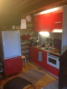 Elle comprend une petite cuisine avec des placards rouges et un évier. dans l'établissement Ranta Äärelä, à Vuotso