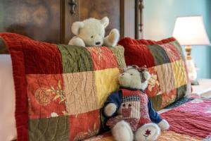 2 ours en peluche assis au-dessus d'un lit dans l'établissement Magnolia Plantation & Cottages, à Gainesville