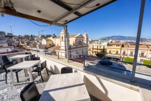 a balcony with tables and chairs and a view of a city at Disiu Case Vacanza in Balestrate