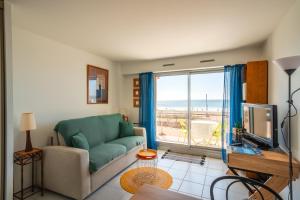 un salon avec un canapé et une grande fenêtre dans l'établissement L'écrin bleu - Vue Mer - Wifi - Central, à Pornichet