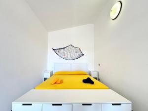 a bedroom with a bed with a yellow blanket and a clock at Casa Proserpio in Villasimius