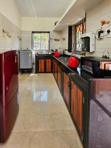a large kitchen with wooden cabinets and a counter top at Goan Villa,2BHK, 4Balconies, Beachside,BBQ, Wi-Fi,Work, Group in Candolim