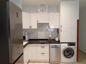 a white kitchen with a washing machine and a clock at Hermoso Apartamento cerca de la playa y centro in Tarifa