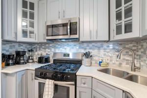 a kitchen with white cabinets and a stove and a microwave at Oversized Family Beach Block Duplex with Game Room in Atlantic City