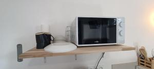 a microwave oven sitting on a wooden shelf at Chambre avec Kitchenette in Évran