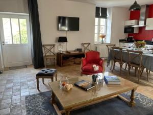 a living room with a table and a red chair at La Maison des Belles Filles in Pernand-Vergelesses