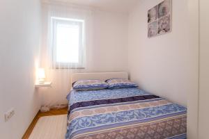 a small bedroom with a bed with a window at Apartment Soni A4 in Krk