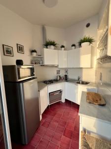 a kitchen with white cabinets and a red tile floor at Il Conventino delle Cinque Terre - Sea View - AC&WiFi - Vernazzarentals in Vernazza