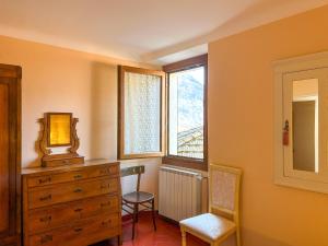 ein Schlafzimmer mit einer Kommode, einem Stuhl und einem Fenster in der Unterkunft Ca'del Gasperin in Claino