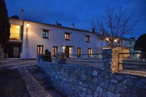 a large white house with a stone wall at night at Casa Rural Finca Buenavista in Valdeganga de Cuenca