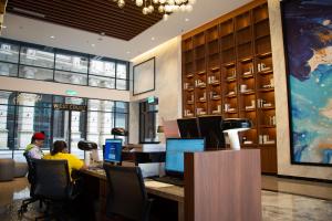 eine Lobby mit zwei Personen, die an einem Schreibtisch mit Computern sitzen in der Unterkunft 12 Mossaz skypool 5mins to 1U and Ikea atEmpire City by Light House in Petaling Jaya