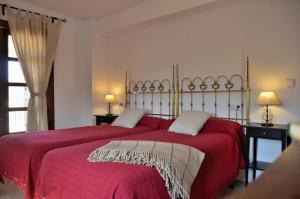a bedroom with two beds with red sheets and two lamps at Casa Rural Finca Buenavista in Valdeganga de Cuenca +65 photos