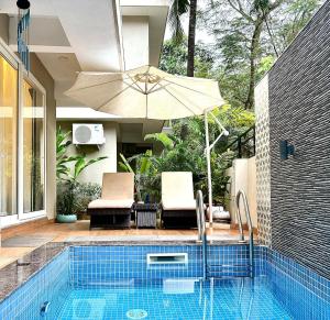 una piscina con sombrilla y 2 sillas y una piscina en The Green Door Villa Varca Beach with Private pool, en Varca