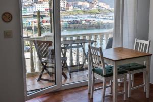 a table and chairs on a balcony with a view of a harbor at Apartamentos Arnela in Camariñas