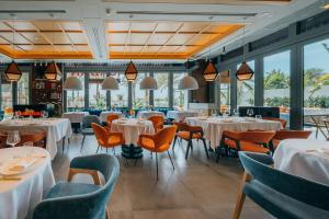 a restaurant with white tables and chairs and windows at Radisson Beach Resort Palm Jumeirah in Dubai