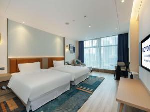 a hotel room with two beds and a flat screen tv at Novotel Wuxi in Wuxi