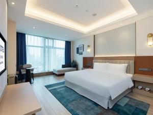 a bedroom with a large white bed and a desk at Novotel Wuxi in Wuxi +96 photos