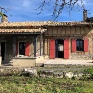 an old house with red shutters on it at Le Marronnier in Villeréal