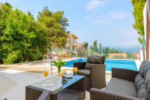 une terrasse avec une table, des chaises et une piscine dans l'établissement Tandem Apartments with Swimming pool, à Cavtat