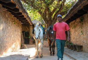 a man walking a horse drawn carriage down a street at Le Relais de la Reine de l'Isalo in Ranohira