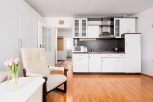 Apartment Valencia في كارلوفي فاري: مطبخ مع دواليب بيضاء وطاولة مع إناء من الزهور