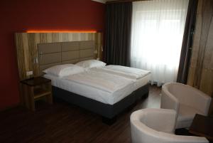 a bedroom with a large bed and two chairs at Hotel-Restaurant Schweinberger in Stetten