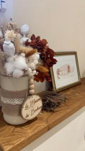 a sign sitting on a shelf with flowers and a picture at La Loubière - le gîte au cœur de la nature in Combret