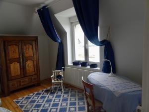 una camera da letto con un letto e una finestra con tende blu di Ty Mamm Doué a Ploubazlanec