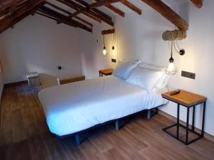 a bedroom with a white bed and a wooden floor at La Posada de Doña Carmen in Villanueva de Alcardete