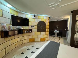 a lobby with a stone wall with a flat screen tv at Shop Motel in Campina Grande