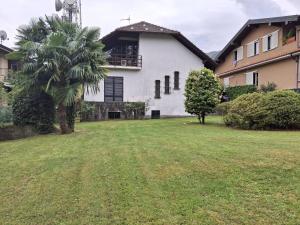 a house with a palm tree in front of a yard at La casa di Arnika in Baveno
