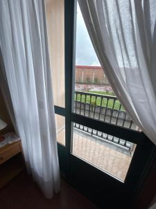 a window with white curtains in a room at Pensión Arcano in Arzúa