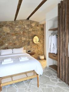 a bedroom with a white bed and a stone wall at Villa Vivari Suites in Vivari +62 photos