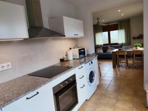 a kitchen with white appliances and a living room at Allotjament Cal Bru in Sant Llorenç de Morunys