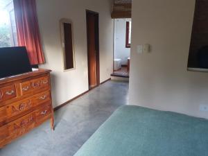 a bedroom with a bed and a dresser with a television at PiedrasBlancas in Mar de las Pampas