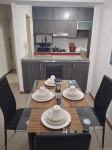 a dining room with a table and chairs and a kitchen at Alojamiento Familiar en zona exclusiva de Chiclayo in Chiclayo