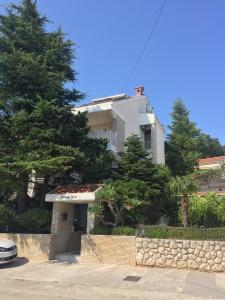 a white house with a stone wall and trees at Apartments Villa Ana in Dramalj