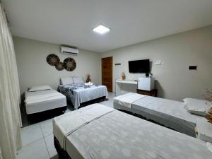 a hotel room with two beds and a television at Pousada du Vento in Cruz