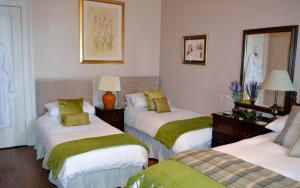 a room with three beds with green and white sheets at Maybank Guest House in Helensburgh