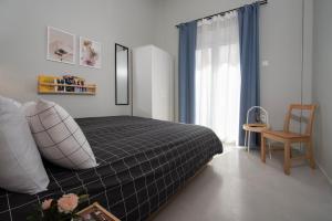 Un dormitorio con una cama y una silla y una ventana. en Nasos Aegina Apartment, en Aegina Town