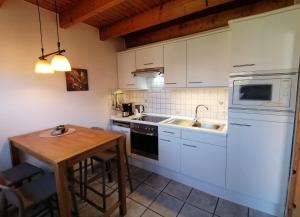 a kitchen with white cabinets and a wooden table at Dat Osterhuus - gemütlich, familienfreundlich, Wallbox, WLAN, 3-Sterne, im Zentrum von Neßmersiel in Neßmersiel