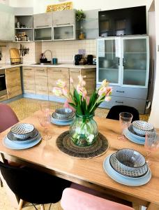 einem Holztisch mit Platten und einer Vase aus Blumen in der Unterkunft Two Bedroom Apartment - Alexandrovska - Top Location - Central Bus, Train and Marine Stations, next to Sea Garden and Beach in Burgas City